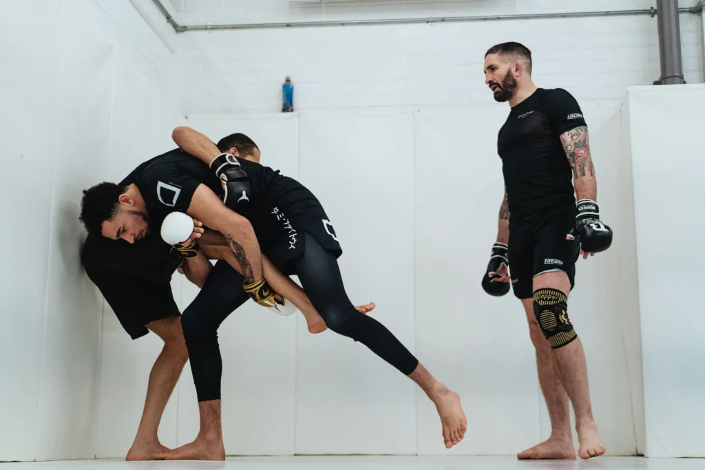 Two Raptors fighters drilling MMA techniques during training inside the gym, focusing on grappling and striking.
